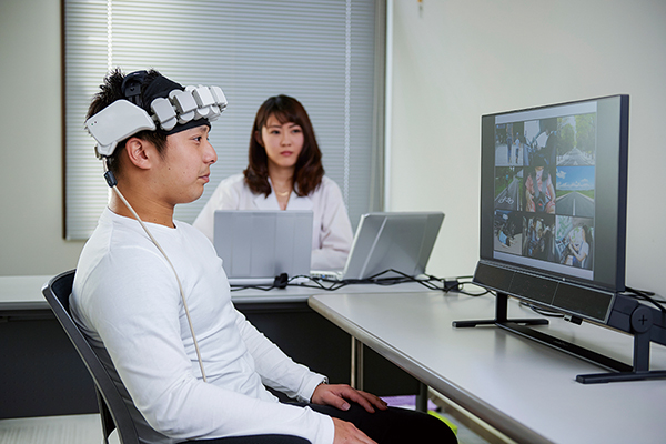 【Functional near
infrared spectroscopy(fNIRS)】<br>fNIRS is a device that visualizes the activity state of the brain surface by irradiating the head with high biopermeability near infrared light and detecting a part of the light reflected from the living body.